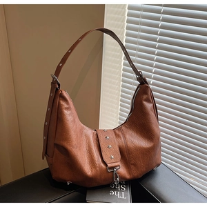 Detail of vintage caramel brown hobo bag with silver star rivets and soft leather texture