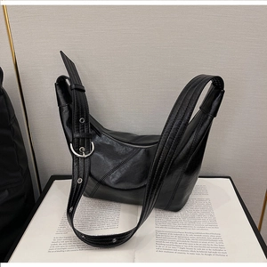 Detail of black faux leather half-moon bag with diagonal stitching and adjustable silver buckle