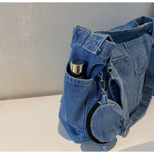 Macro view of washed denim tote side pocket and round coin purse charm attachment