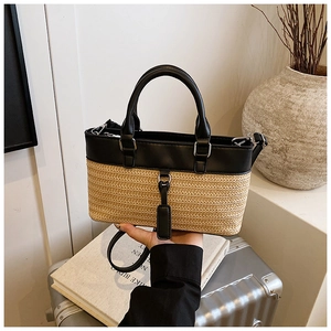 Close-up of woven straw and black leather handbag with metallic hooks and handle