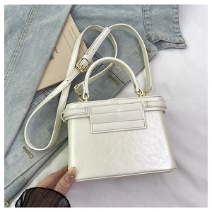 Detail view of mini white leather box bag with handle on denim jacket background