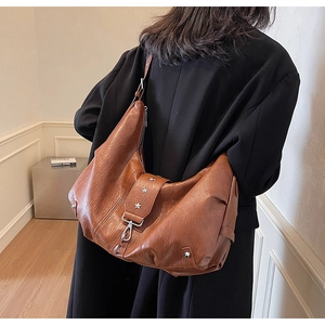 Detail of vintage brown leather tote bag with star rivets and soft texture on shoulder