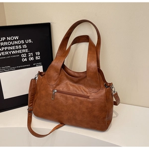 Detailed view of the brown leather texture and rear metal zipper pocket of the handbag