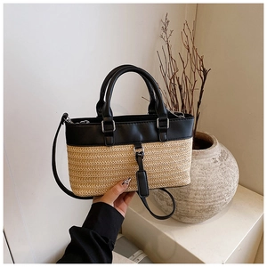 Detail view of straw woven texture and black leather stitching on a tote bag