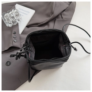 Top view of black lychee grain leather mini bag with metal zippers and drawstring detail