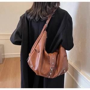 Detailed view of caramel brown slouchy leather tote featuring silver star stud accents