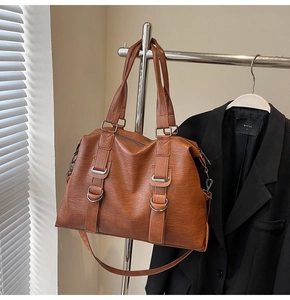 Detail view of brown faux leather texture and silver buckle on large tote bag
