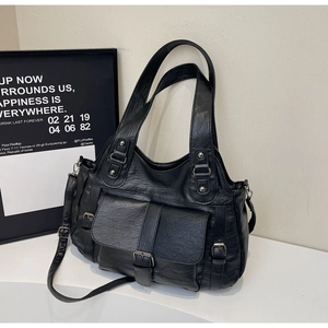 Detail of black oil wax leather tote bag with large front flap pocket and metal buckle