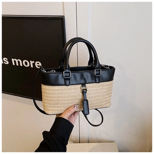 Close-up of woven straw handbag with black leather trim and elegant metallic lock