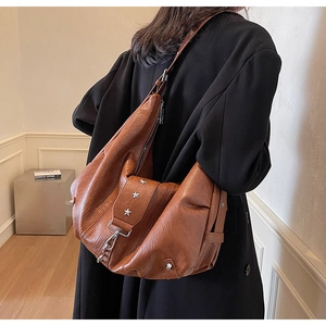 Detailed view of brown leather tote bag with star studs and vintage texture worn by a model