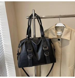 Close-up of black pebble grain leather texture and metallic buckle on tote bag