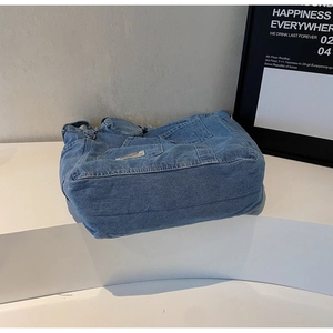 Detail view of washed denim tote bag with external pocket and mini coin purse attachment