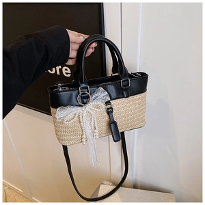 Detail of straw woven bag with black leather patchwork and white lace bow with pearls