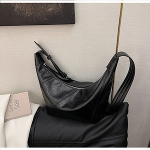 Detail view of black crescent shoulder bag with pebbled leather texture and stitching