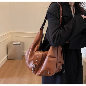 Detail of vintage brown leather tote bag with star rivets and metallic lock hardware