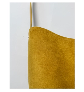 Macro view of ginger yellow frosted leather texture and precise stitching on the bucket bag