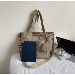 Spacious khaki nylon tote bag showing interior capacity with laptop and round coin purse