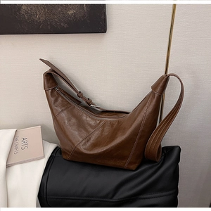 Detail view of deep brown crescent bag with smooth oil-wax finish and adjustable strap