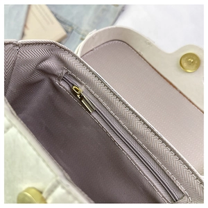 Detail view of the interior zip pocket and herringbone lining of this chic cream box bag