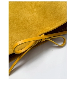 Detail of yellow matte leather texture with elegant leather bowknot on side of the bag
