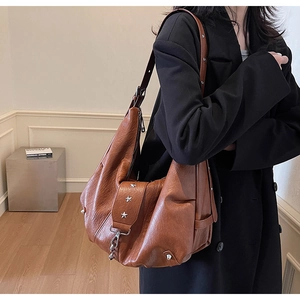Detail view of brown vintage leather tote with silver star rivets and soft texture
