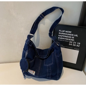 Detail of blue denim hobo bag with white stitching, multi-pockets and a round coin purse charm