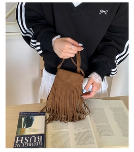 Détail d'un sac à main en daim marron avec de longues franges et une texture mate