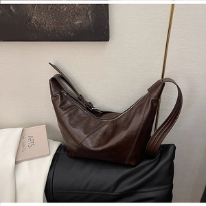 Close-up of the smooth zipper closure and shiny PU leather texture on the crescent bag