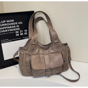 Detailed view of taupe soft leather handbag with metal buckle and rivet accents