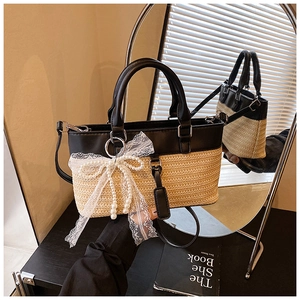 Detail of straw patchwork handbag with lace bow and pearl tassels on mirror background