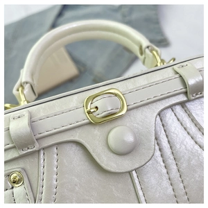 Close-up of cream leather vintage box bag featuring gold hardware and stitched handle detail