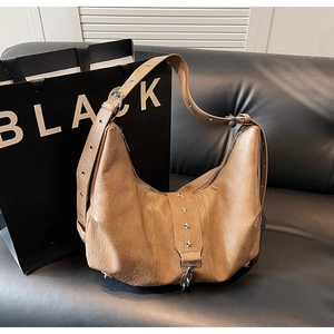 Detail of caramel brown hobo bag featuring silver eyelets and star rivet accents