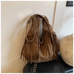 Detail of brown faux suede hobo bag featuring long tassels and gold metal hardware rings
