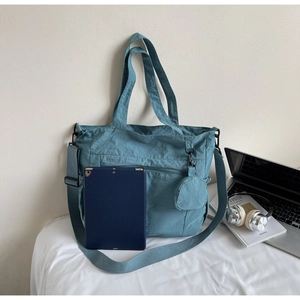 Detailed view of Morandi blue nylon tote bag showing front zipper pocket and tablet capacity