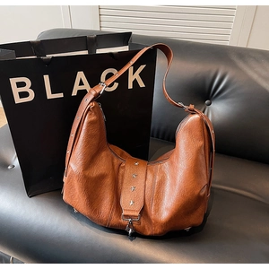Detail of a brown hobo bag with star rivet trim and silver eyelet strap on leather