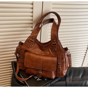 Detail of a brown leather handbag with metallic buckles and vintage texture on a book