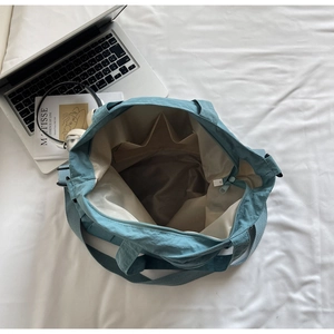 Detail view of large blue nylon tote interior with compartments and lifestyle items