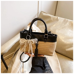 Detail of hand-woven straw tote bag with black PU leather, lace bow, and pearl beads