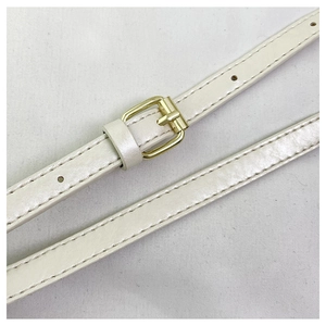 Detail of creamy white denim bag strap with gold buckle and precise stitching