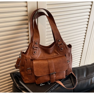 Close-up of vintage brown leather handbag featuring antique metal buckle and front pocket