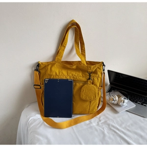 Detail view of large nylon tote bag in ginger yellow with laptop and accessories