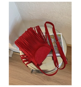 Vue détaillée d'un sac à bandoulière en daim rouge avec couches de franges et boucles en métal
