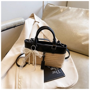 Detailed shot of straw and black leather handbag with pearl lace bow on white blazer