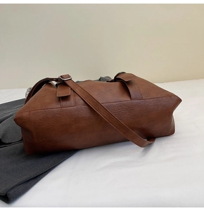 Close-up of brown faux leather tote bag with lychee texture and silver metal buckle