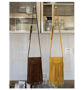 Détail du sac bandoulière vintage en daim avec de longues franges en marron et jaune