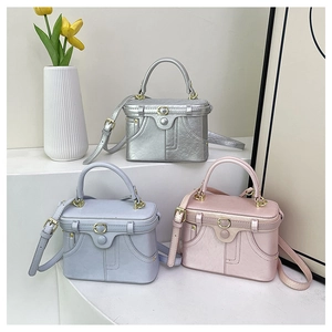 Three retro mini box bags in silver, blue, and pink displayed on a white tiered stand