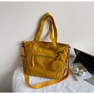 Detail of yellow nylon tote bag with mini coin purse and adjustable strap in office setting