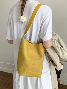 Minimalist yellow suede bucket bag shown on model's shoulder for a daily casual look
