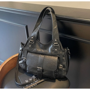 Detailed macro view of black PU leather tote bag with silver metal buckles and retro texture