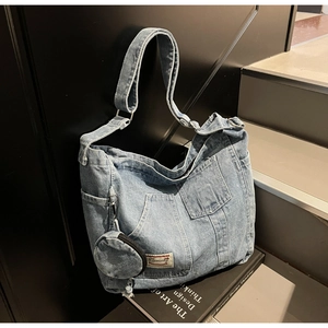 Macro detail of washed denim tote with utility pockets and a round zipper coin pouch